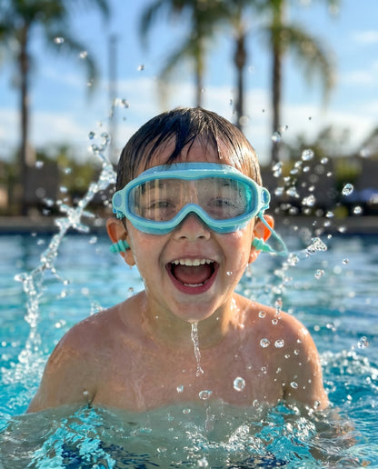Kid mid-action emerging from pool wearing Reef goggles
