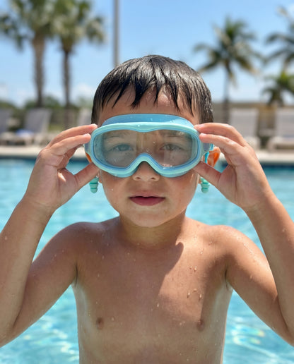 Boy in pool wearing Reef goggles, hands adjusting frame