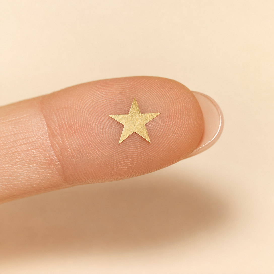 Single gold star on a fingertip — scale reference